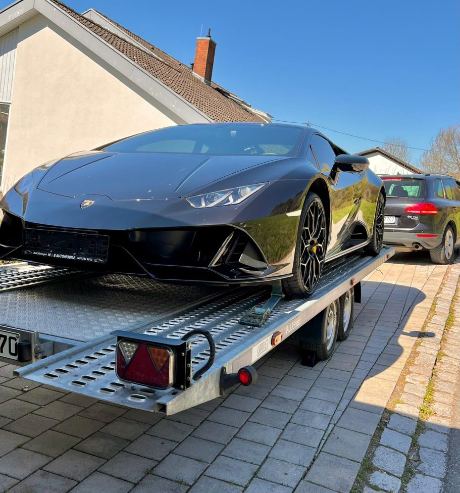 Exklusiver Sportwagentransport – Sicher & Professionell Sicherer Transport eines schwarzen Lamborghini Huracán auf einem spezialisierten Autoanhänger.